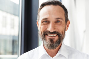 Bearded pleased businessman smiling and looking at camera