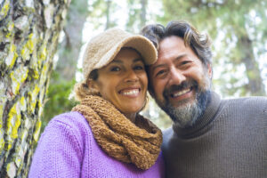 Cheerful and happy adult couple smile together in forest
