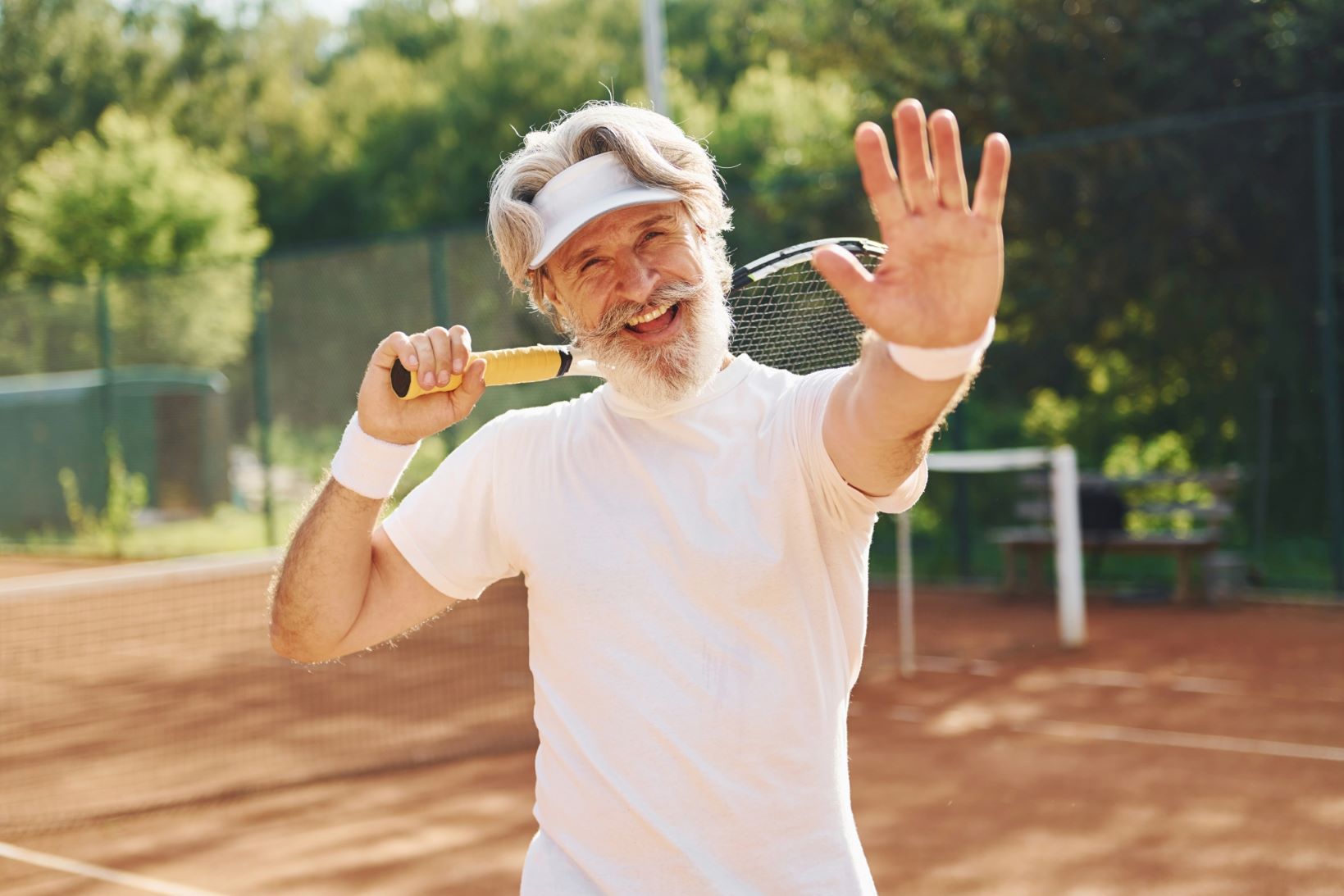 Senior modern stylish man with racket playing outdoors.