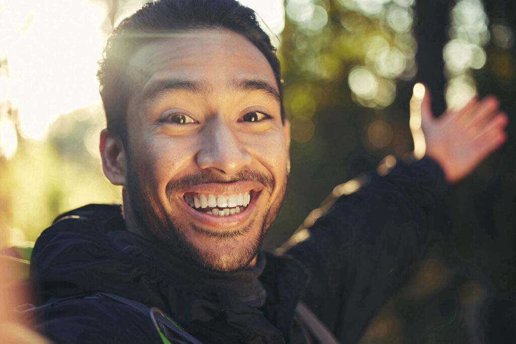 Hiking man smiling at selfie in forest