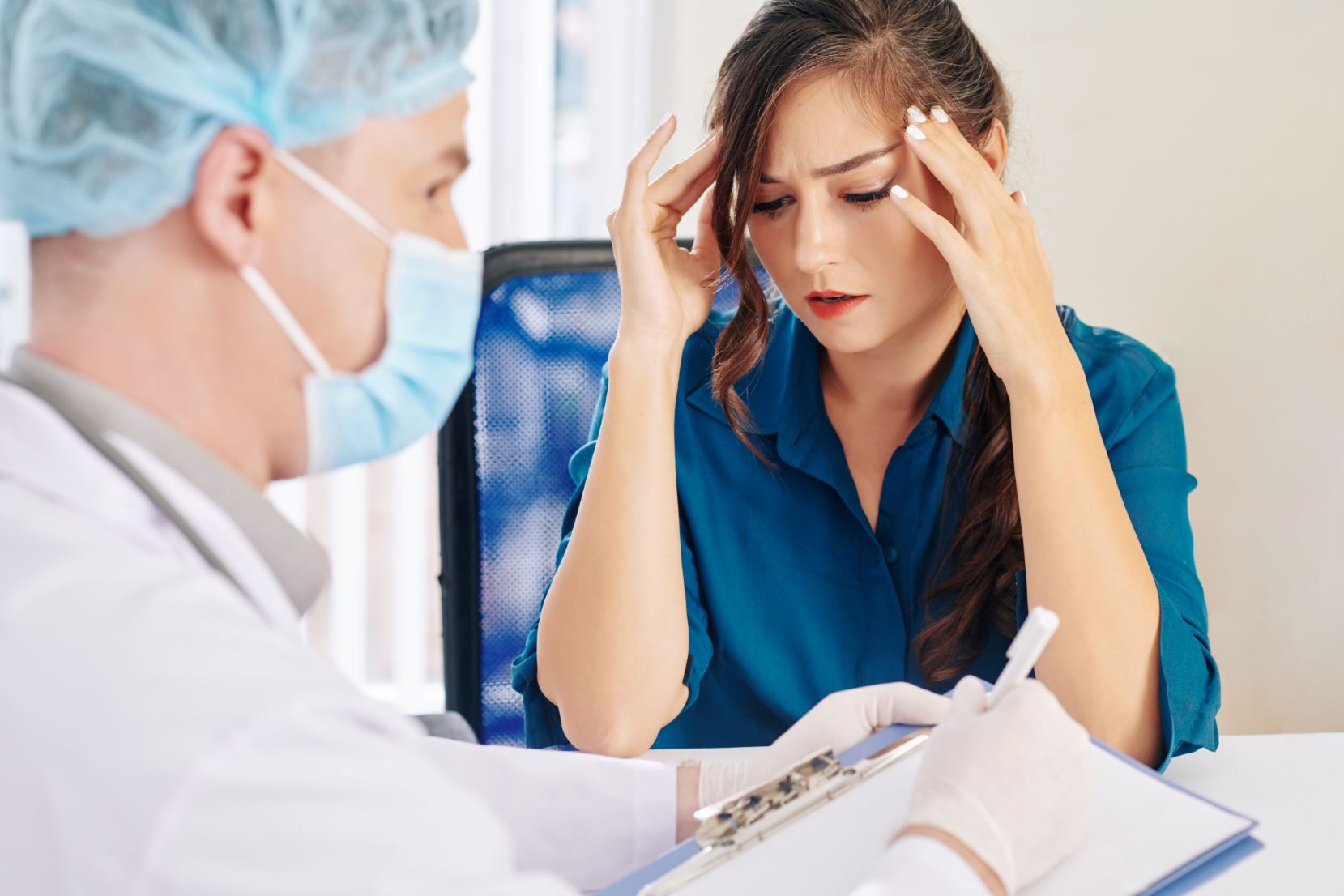 Woman suffering from severe headache seeing a doctor.