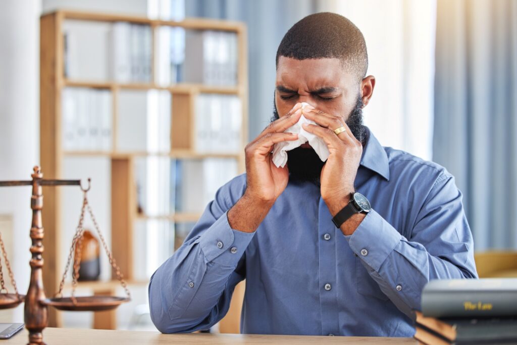 Man with sinusitis blowing his nose.